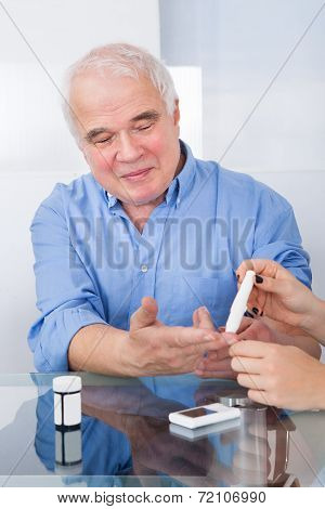 Doctor Using Lancelet On Senior Man