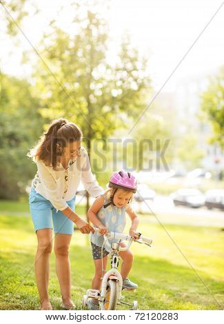 Mother Helping Baby Girl Riding Bicycle