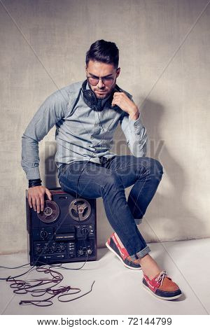 Handsome Man Listening To Music On A Magnetophone Against Grunge Wall