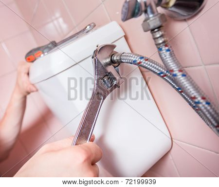 Plumber Fixing Toilet With Wrench