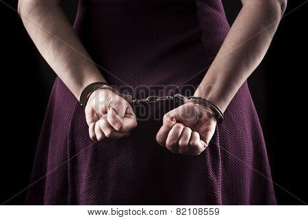 Submissive Woman Wearing A Purple Dress In Metal Handcuffs On Black Background