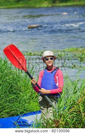 Girl near a kayak on the river