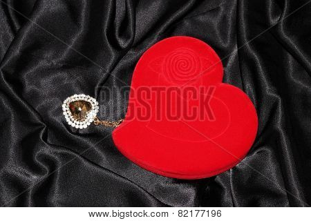 Heart-shaped jewelry casket with pendant placed on a black silk