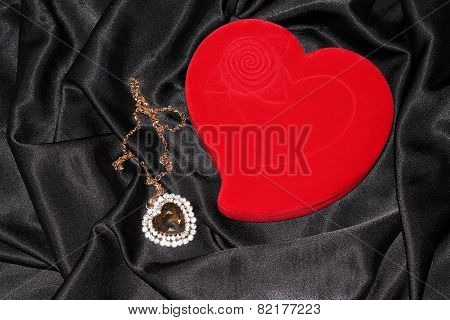 Heart-shaped jewelry casket with pendant placed on a black silk
