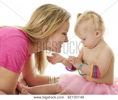 An admiring mother admiring the bangles that interest two year old daughter.  On a white background.l