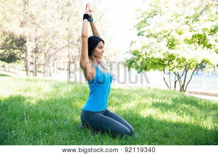 Beautiful woman doing yoga exercises on the green grass in park