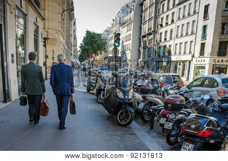 Two male executives walk along Rue de Turbigo in Paris, France