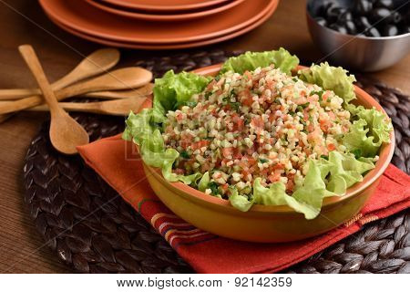 Tabbouleh with bulgur, tomatoes, parsley, and lettuce on a rustic table