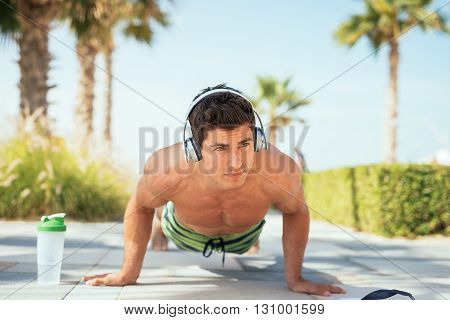 Man doing push ups on the beach.