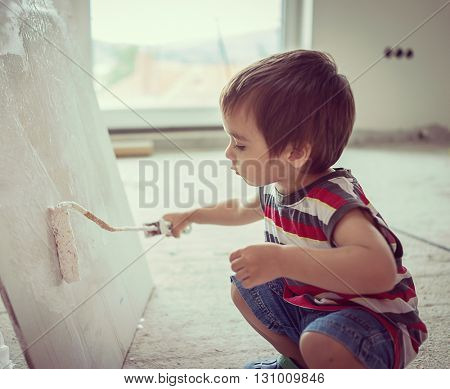 Little cute boy painting on a wall