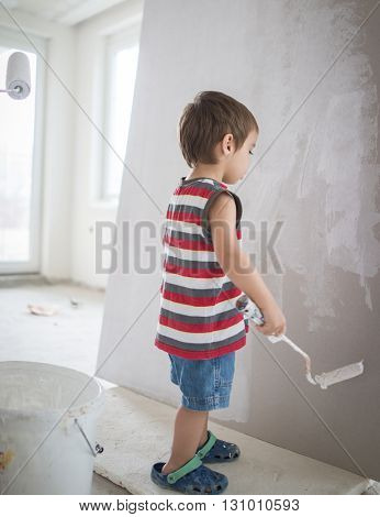 Little cute boy painting on a wall