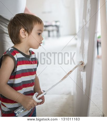 Little cute boy painting on a wall