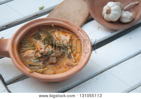 Morning glory in sour red curry Traditional Thai curry on white wood
