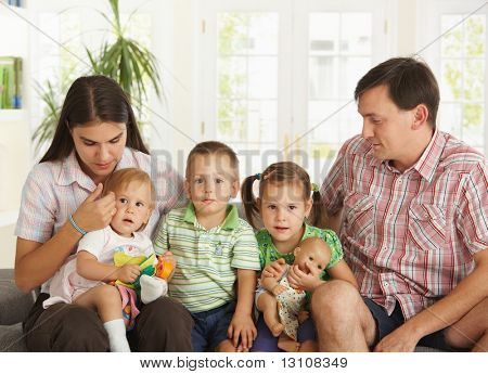 Çekirdek aile ile evde koltukta oturan 3 çocuk portresi.?