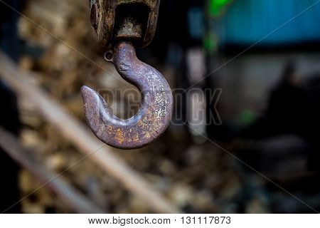 big rusty steel hook weighs on the background of wooden bars