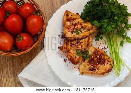 A photo of fried chicken fillet with parsley and tomatoes