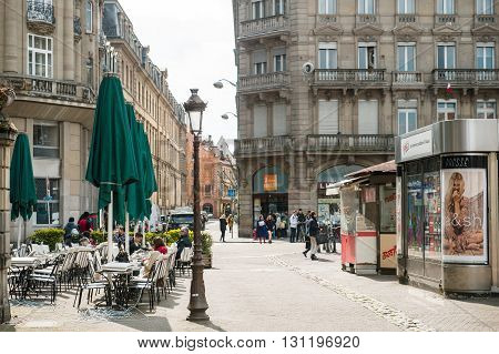 STRASBOURG FRANCE - APR 19 2016: Place Broglie with people enjoying afternoon cafe at terace press kiosk selling magazines and people commuting