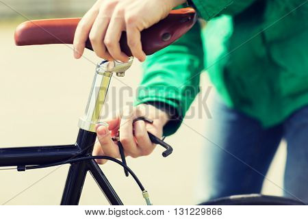 people, vehicle, eisure and lifestyle - close up of man adjusting fixed gear bike saddle high