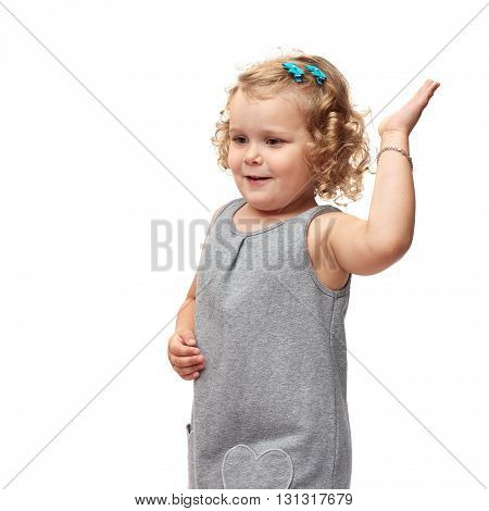 Young little girl with curly hair in gray dress standing and giving high five over isolated white background