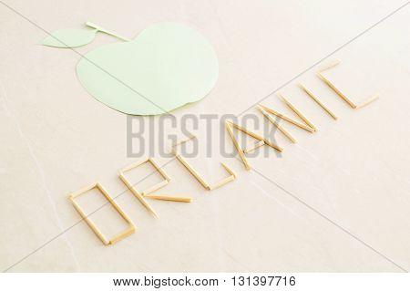 The word organic and abstract green apple on beige background. Organic concept with copy space.