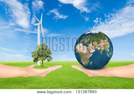 Green Earth concepthand holding tree with wind turbine and earth against green field and blue sky background.Elements of this image furnished by NASA