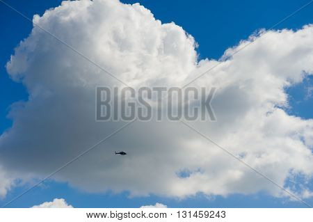 Silhouette helicopter on a background of huge clouds in the sky
