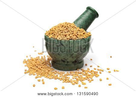 Organic Fenugreek (Trigonella foenum-graecum) on marble pestle and white background.