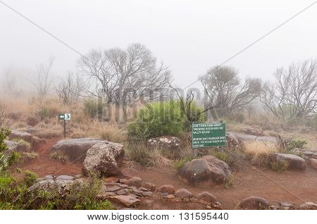A warning sign and route marker in thick fog on the Crag Lizard trail near the Valley of Desolation viewpoint