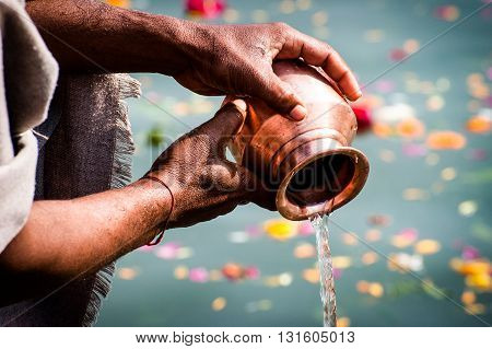 Prayer hands pouring sacred water to the river during the daily worship
