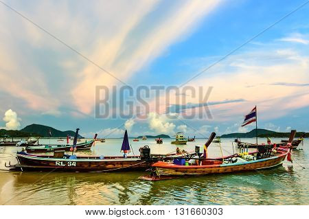 Rawai Thailand - August 17 2014: Traditional long-tail boats & speed boats used for tourist trips & fishing moored in bay at sunset off Rawai beach on southern tip of Phuket southern Thailand