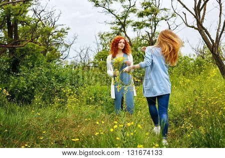 Best friends forever. Friends meet in the park. BFF. A girl holding a bouquet of wildflowers. A friend runs to meet.