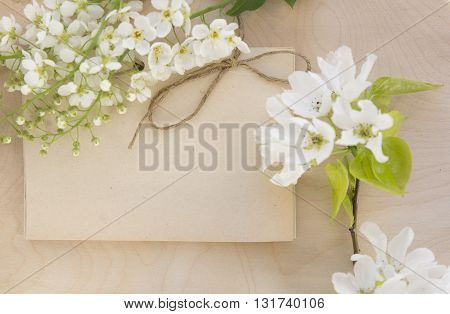 Open vintage handmade sketchbook with white bird-cherry flowers over wooden table background. Mock up retro style. Old paper notepad. Vintage retro mockup. Rough rope. Summer mock-up. Wooden background.