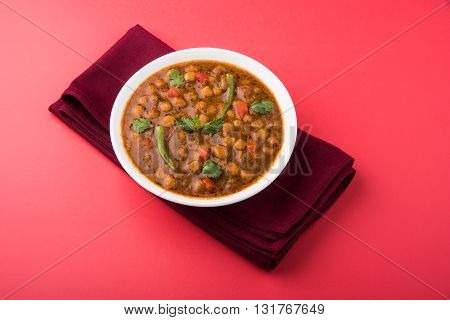 spicy chick peas also known as Chola Masala or Chana Masala or Chole served with fried puri, pickle and green salad
