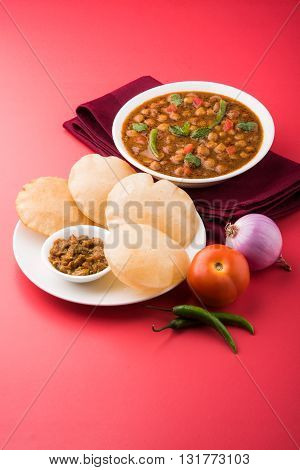 spicy chick peas also known as Chola Masala or Chana Masala or Chole served with fried puri, pickle and green salad