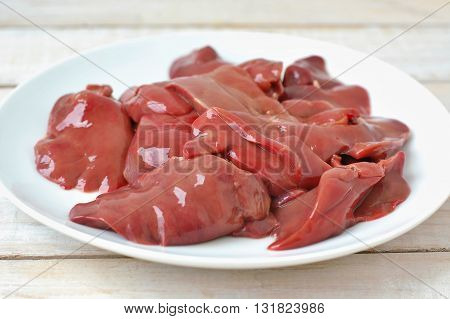 Raw Liver On The White Plate On The Wooden Background