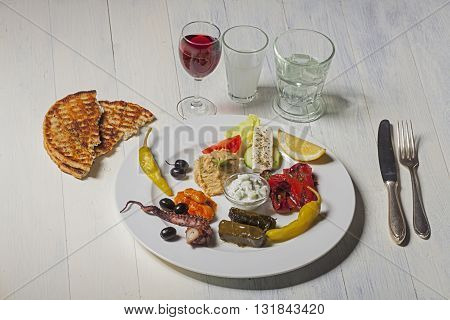 variety of greek appetizers with wine and ouzo