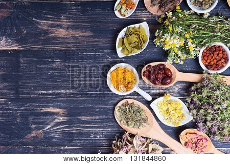 Herbs berries and flowers on color wooden table background