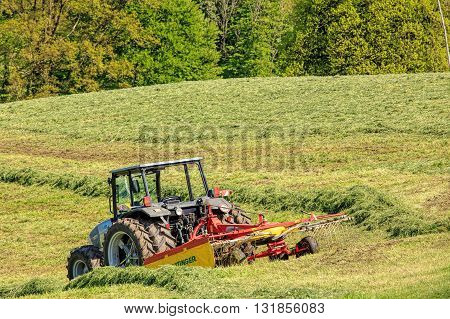 Zug, Switzerland - 6 May, 2016: countryside view with a tractor standing on a hill. The town of Zug is the capital of the Swiss canton of Zug.