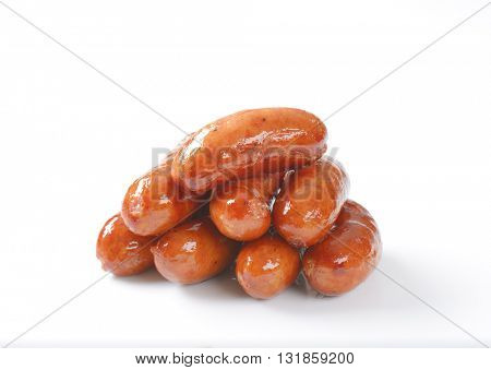 stack of grilled short sausages on white background