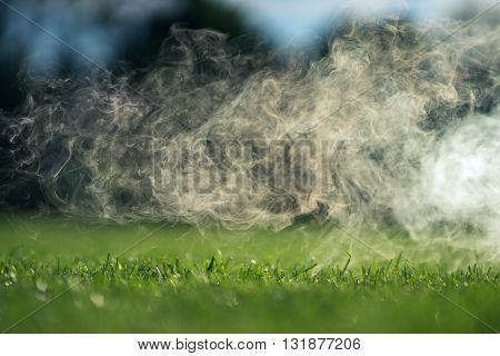 The smoke over the green grass lawn on a Sunny summer day.