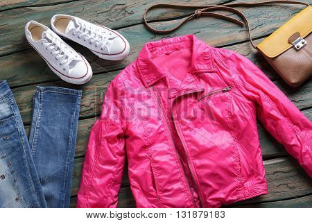 Pink jacket and white shoes. Jeans and brown bicolor bag. Girl's new outerwear on shelf. Stylish jacket from brand store.