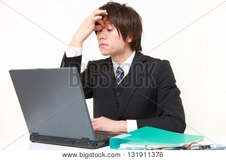 portrait of young Japanese businessman suffers from Asthenopia on white background