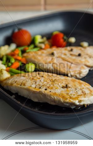 Chicken stean grilling on pan with vegetables