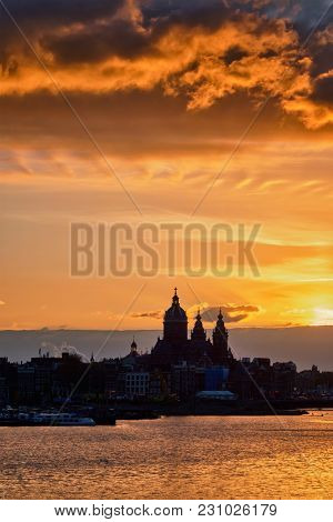 Amsterdam cityscape skyline with  Church of Saint Nicholas (Sint-Nicolaaskerk) on sunset with dramatic sky. Amsterdam, Netherlands