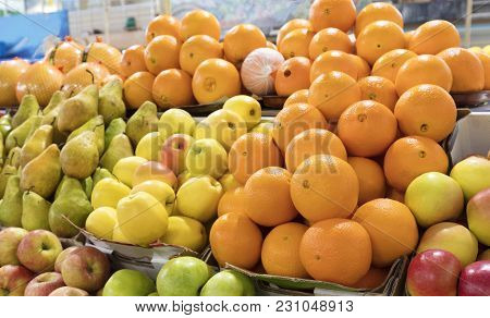 Bright Background Of Fresh Fruits. Oranges, Apples, Pears Lie In The Trays In The Market And Attract