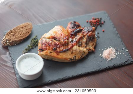 Fried Chicken Steak. Chicken Lays On On Black Slate Board With Sprig Of Thyme, Coarse Salt, Dark Bre