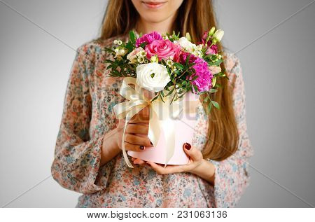 Girl Holding In Hand Rich Gift Bouquet. Composition Of Flowers In A Pink Hatbox. Tied With Wide Whit