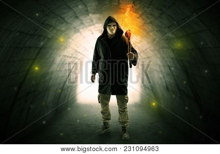 man with burning flambeau walking in a dark tunnel