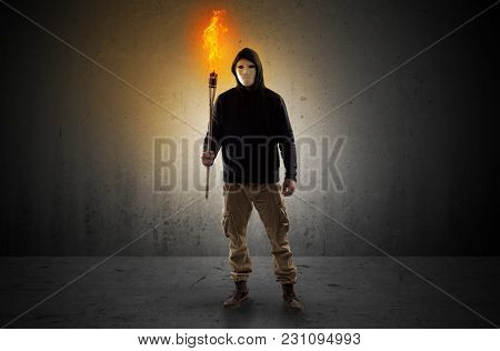 Scary man with burning flambeau walking in an empty space