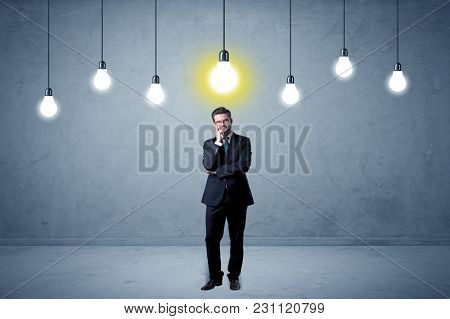 Handsome businessman in an empty space with bulbs above and uninspired face